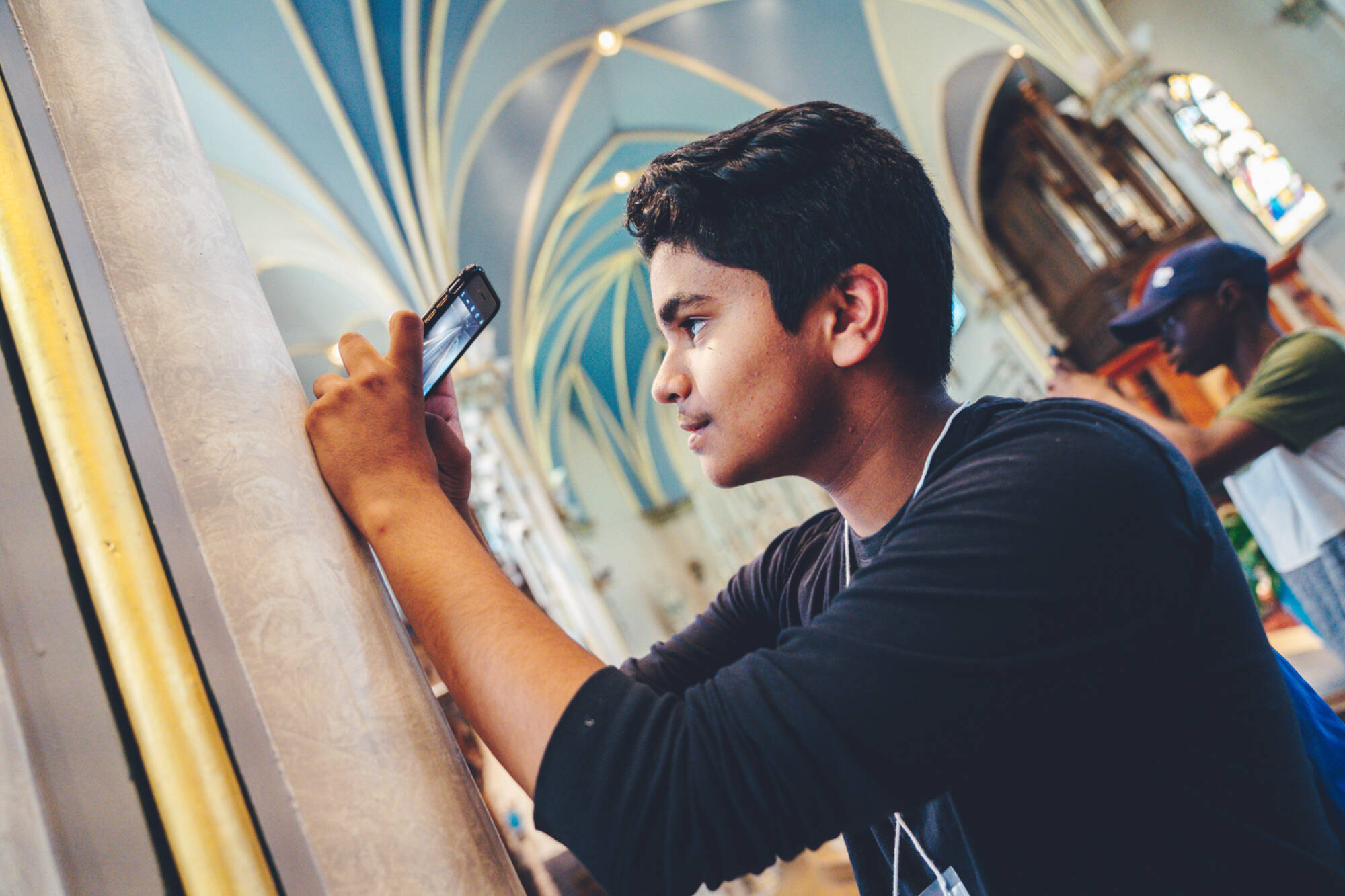 A young male student taking a picture in a cathedral.